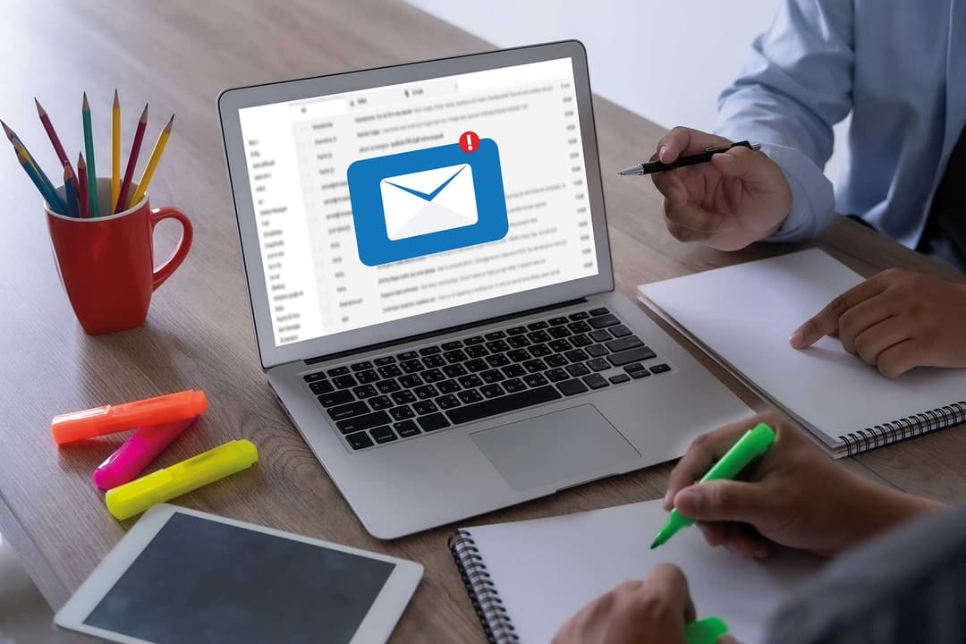 Laptop mit E-Mail-Symbol auf dem Bildschirm, Team plant eine E-Mail-Marketing-Kampagne