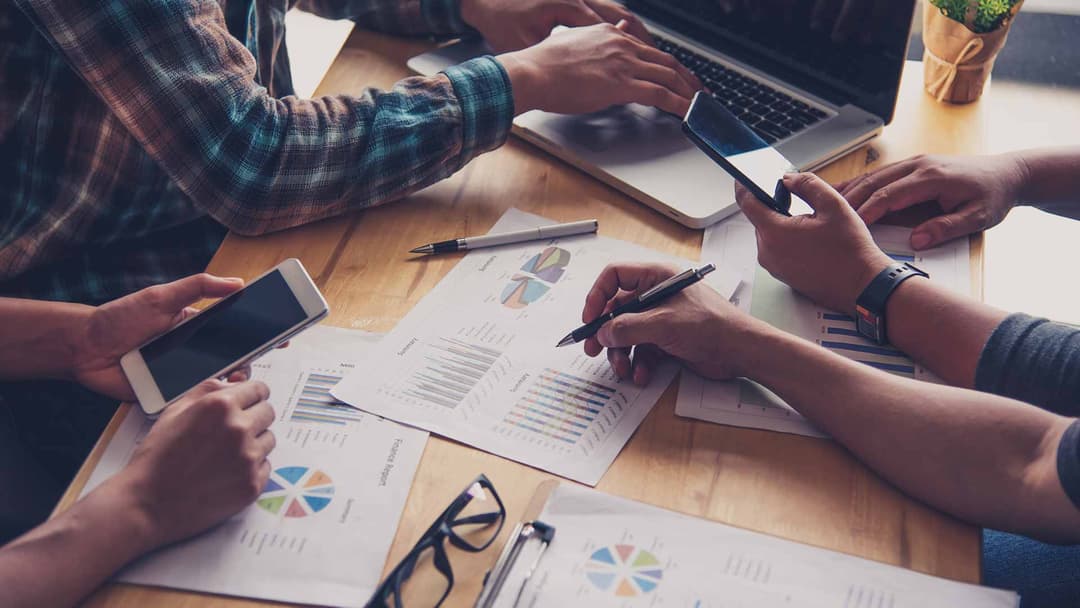 Hände über ausgedruckten Diagrammen und Kennzahlen bei der Planung einer Digital-Marketing-Strategie
