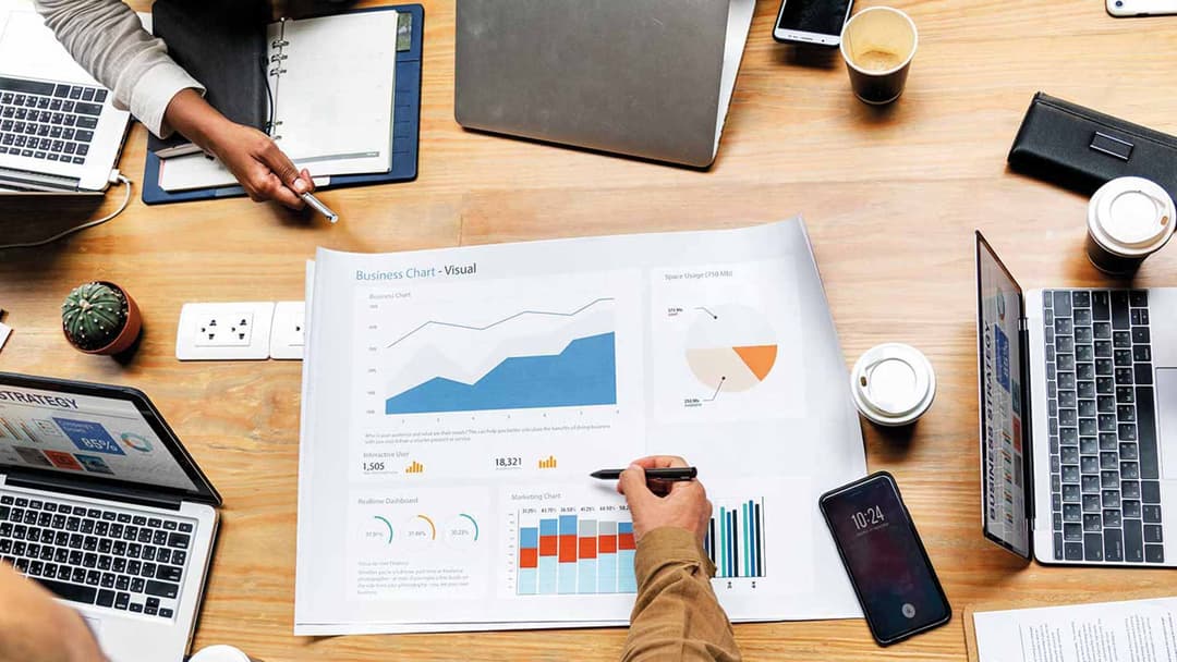 Ausgedruckte Diagramme, Laptops und Smartphone auf einem Schreibtisch: Auswertung für lokales SEO